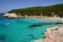 Piccola barca sul mare turchese della bellissima spiaggia di Cala Escorxada