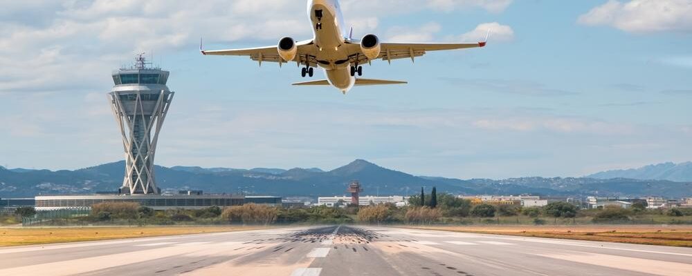 Avión de pasajeros blanco sobrevolando la pista de despegue del aeropuerto de El Prat-Barcelona.