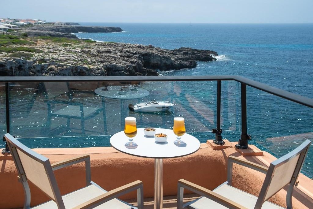 Un tavolino su una terrazza affacciata sulla costa rocciosa di Binibeca, a Minorca