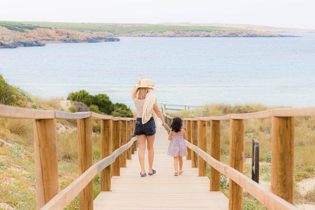 Una madre y una niña en la pasarela de madera que lleva al mar en Son Parc