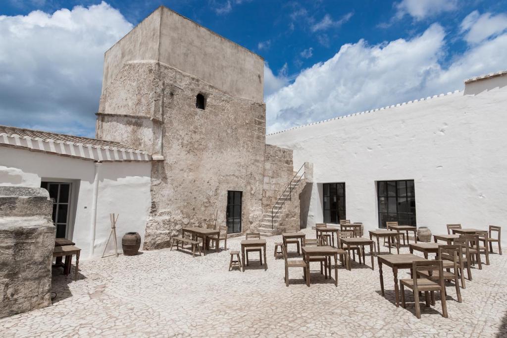 La torre di pietra e i tavoli all'aperto di Torre Vella, nella campagna di Alaior