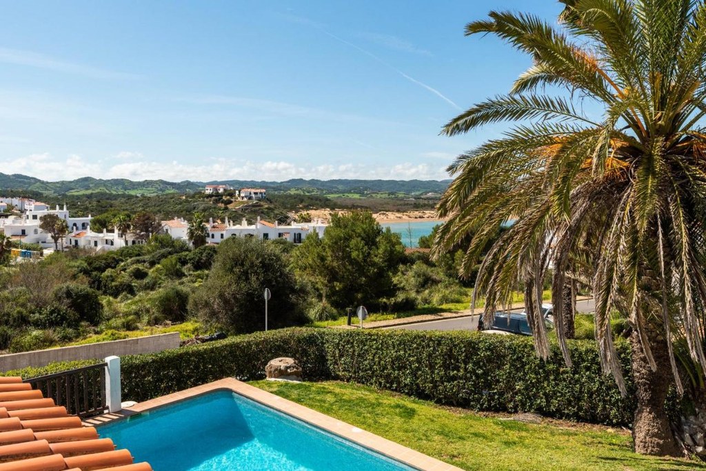 La baia di Fornells vista da una terrazza con la palma, sopra una piscina privata, nel nord di Minorca